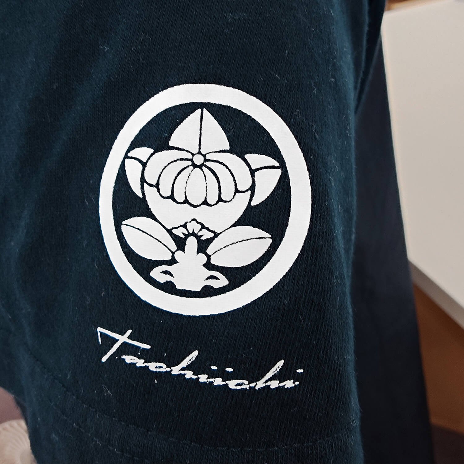 家紋ロゴ（丸に橘一）と筆記体